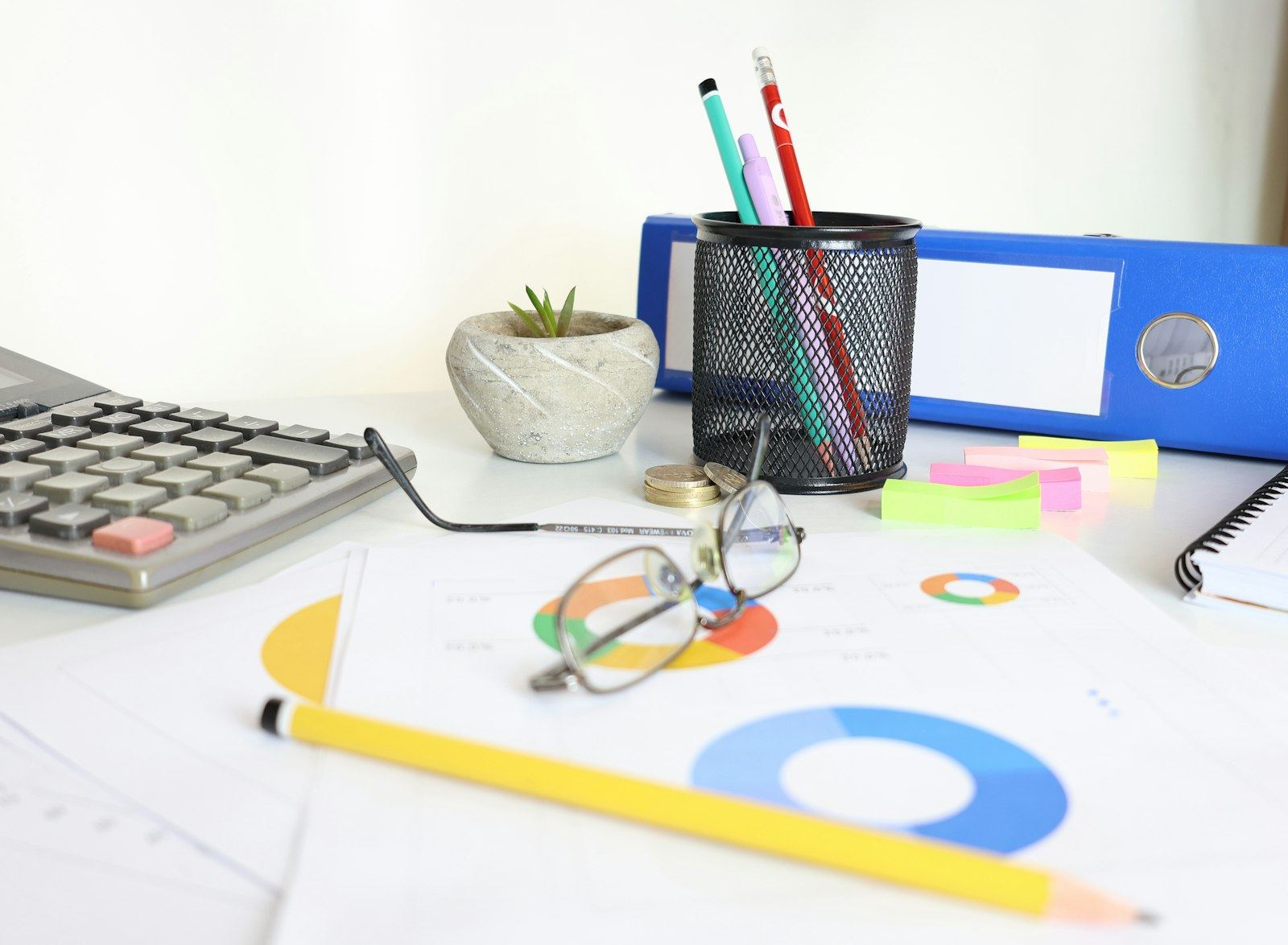 Desk with pens, folders, calculator and sticky notes